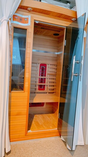 A sauna room with a wooden interior, a glass door, and a control panel. - Tom's Farm House Delightful space for an escape (Musk)