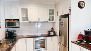 A kitchen with white cabinets, a stainless steel refrigerator, a microwave, an oven, and a coffee maker. - Tom's Farm House Delightful space for an escape (Musk)