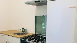 A compact kitchen with a gas stove, oven, and a refrigerator. - Venice Cityview Guesthouse (Mestre)