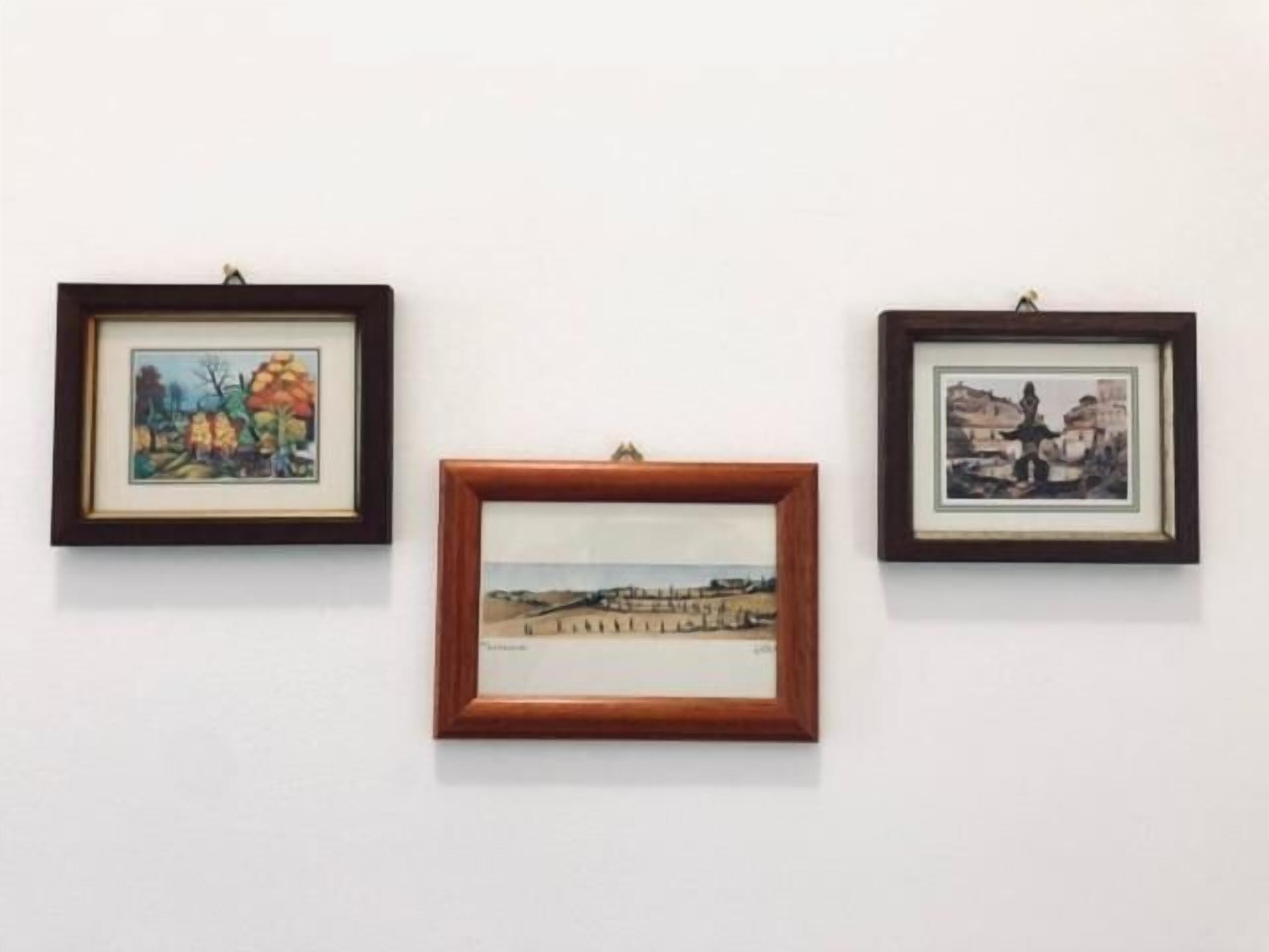 Drei gerahmte Kunstwerke an einer weißen Wand.