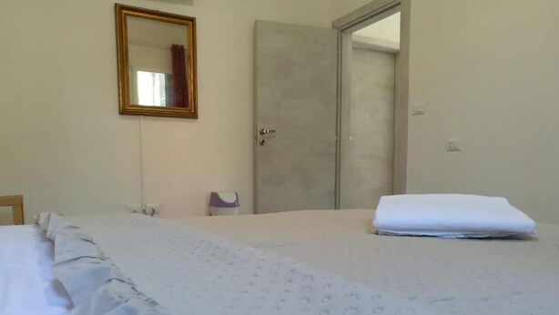 A hotel room with a bed, a door, and a mirror on the wall. - Venice Cityview Guesthouse (Mestre)