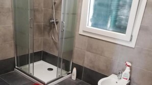 A modern bathroom with a glass-enclosed shower, a bidet, and a red mat on the floor. - Venice Cityview Guesthouse (Mestre)