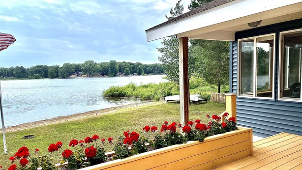A wooden deck with a flower bed and a view of a lake. - Cozy 2 bedroom cottage, lakefront private beach (Township of Branch)