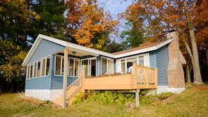A two-story house with a porch, large windows, and a brick chimney. - Cozy 2 bedroom cottage, lakefront private beach (Township of Branch)