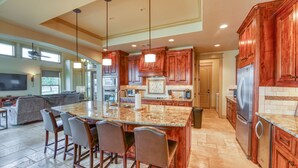 A spacious kitchen with granite countertops, wooden cabinets, and a central island with bar stools.