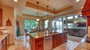 A spacious kitchen with granite countertops, wooden cabinets, and a large island.