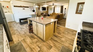 A kitchen with a central island, wooden flooring, a built-in stove, and a dining area with a bench.