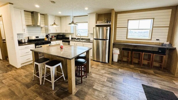 A kitchen with a central island, stainless steel appliances, and a bar area.