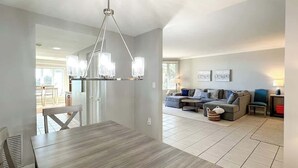 Ein modernes Wohnzimmer mit Essbereich, einer Chandelier und einer Sofagarnitur.