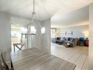 A modern living room with a dining area, a chandelier, and a sofa set.