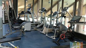Een fitnessruimte met diverse trainingsapparaten, waaronder loopbanden, elliptische trainers en krachttoestellen.