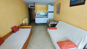 Una habitación con dos camas, kitchenette y comedor.