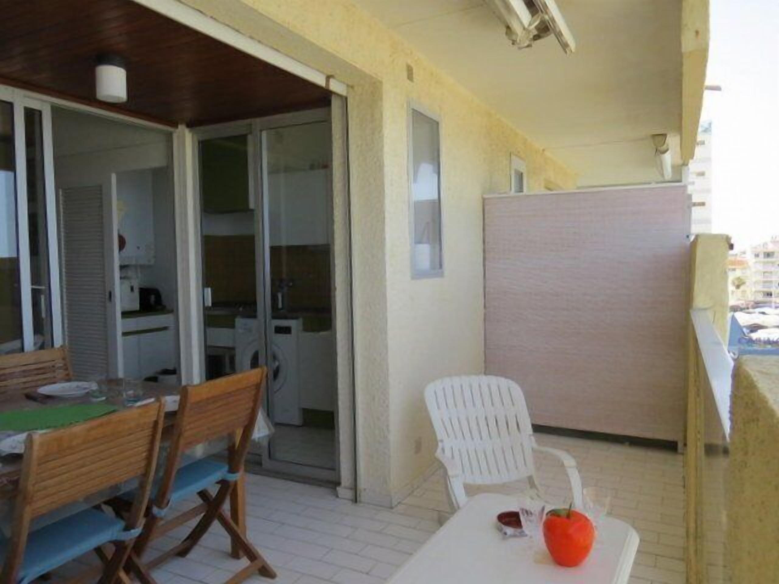A balcony with a table, chairs, and a red apple.