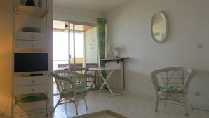 Quarto com escrivaninha, duas cadeiras de vime, espelho e vista para o exterior.
