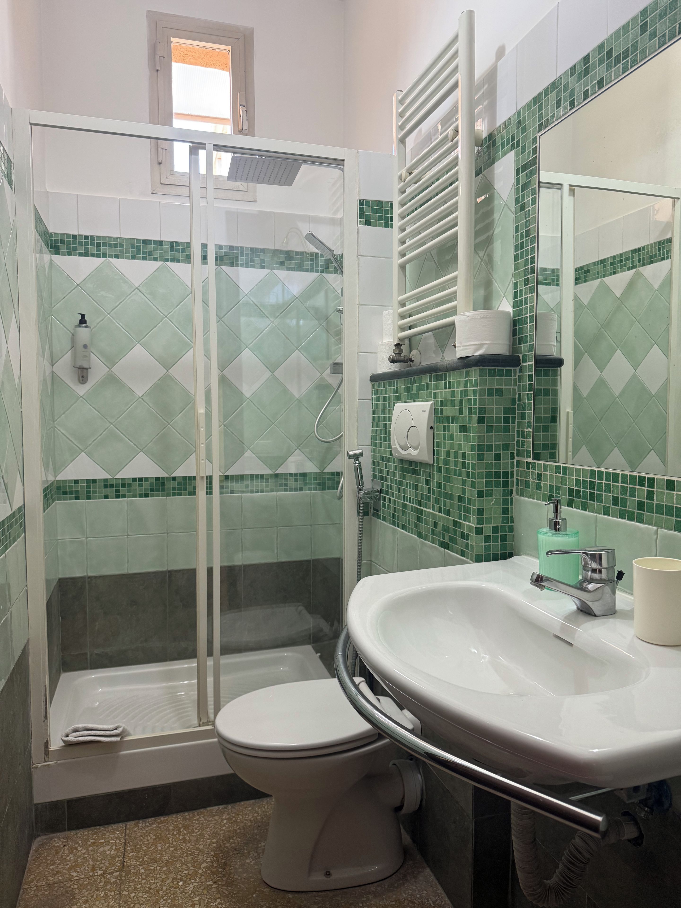 A bathroom with a glass-enclosed shower, a toilet, and a sink with a mirror.
