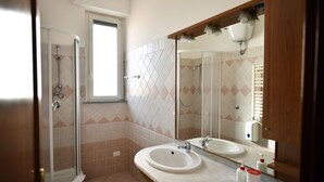 A bathroom with a shower, two sinks, a large mirror, and a window. - Via Curtatone 12 Apartment (Rome)
