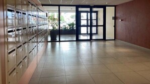 A spacious lobby with a row of metal lockers on the left and a glass door leading outside. - Charming T2 for 4 people terrace sea view, elevator - 4CASI402 (CANET PLAGE)