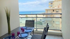 A balcony with a table set for four, overlooking a beach and buildings. - Charming T2 for 4 people terrace sea view, elevator - 4CASI402 (CANET PLAGE)