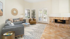 A living room with a fireplace, grey sofa, armchair, and a coffee table.
