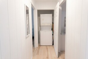 A narrow hallway with a white wall and a door leading to a room. - Little Haven Cottage - Ocean view 2 bedroom cottage with beach access. (Mount Stewart)