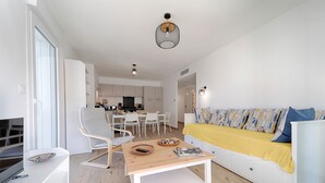 A modern living room with a sofa, a coffee table, and a dining area with chairs and a table. - Charming apartment ideally located - Swimming pool - Air conditioning (Mimizan)