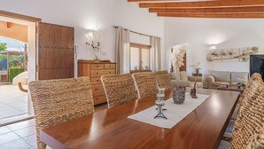A dining area with a wooden table, wicker chairs, and a view of the outdoors. - Villa "Sa Caseta Rustic Villa" with Pool, Terraces & Wi-Fi (Tourist Tax Included) (Cala D'or)