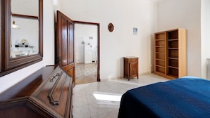 Un dormitorio con cama, armario, cómoda y espejo.