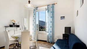 Una habitación con cama, escritorio, silla, televisor y ventana con cortinas.