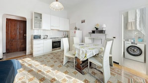 Cocina pequeña con armarios blancos, microondas y lavadora.