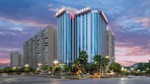 A multi-story hotel with a modern design, featuring a prominent vertical strip of windows and a flat roof. - Fusion International Hotel (Yizhang)