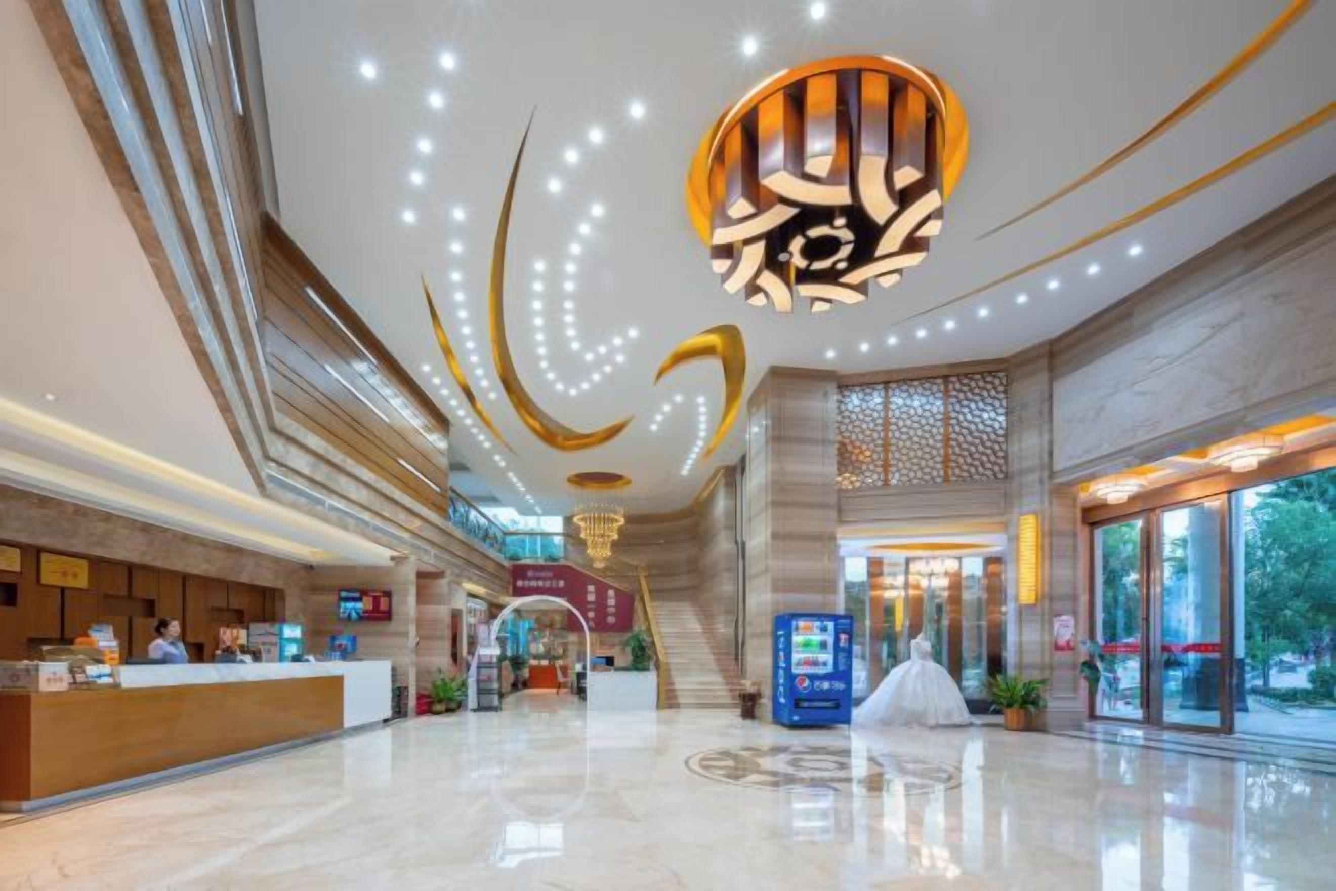 A spacious lobby with a reception desk, a staircase, and a vending machine.