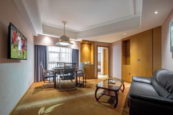Una sala de estar moderna con un sofá de cuero, una mesa de comedor con sillas, un ventanal con cortinas y un armario de madera.
