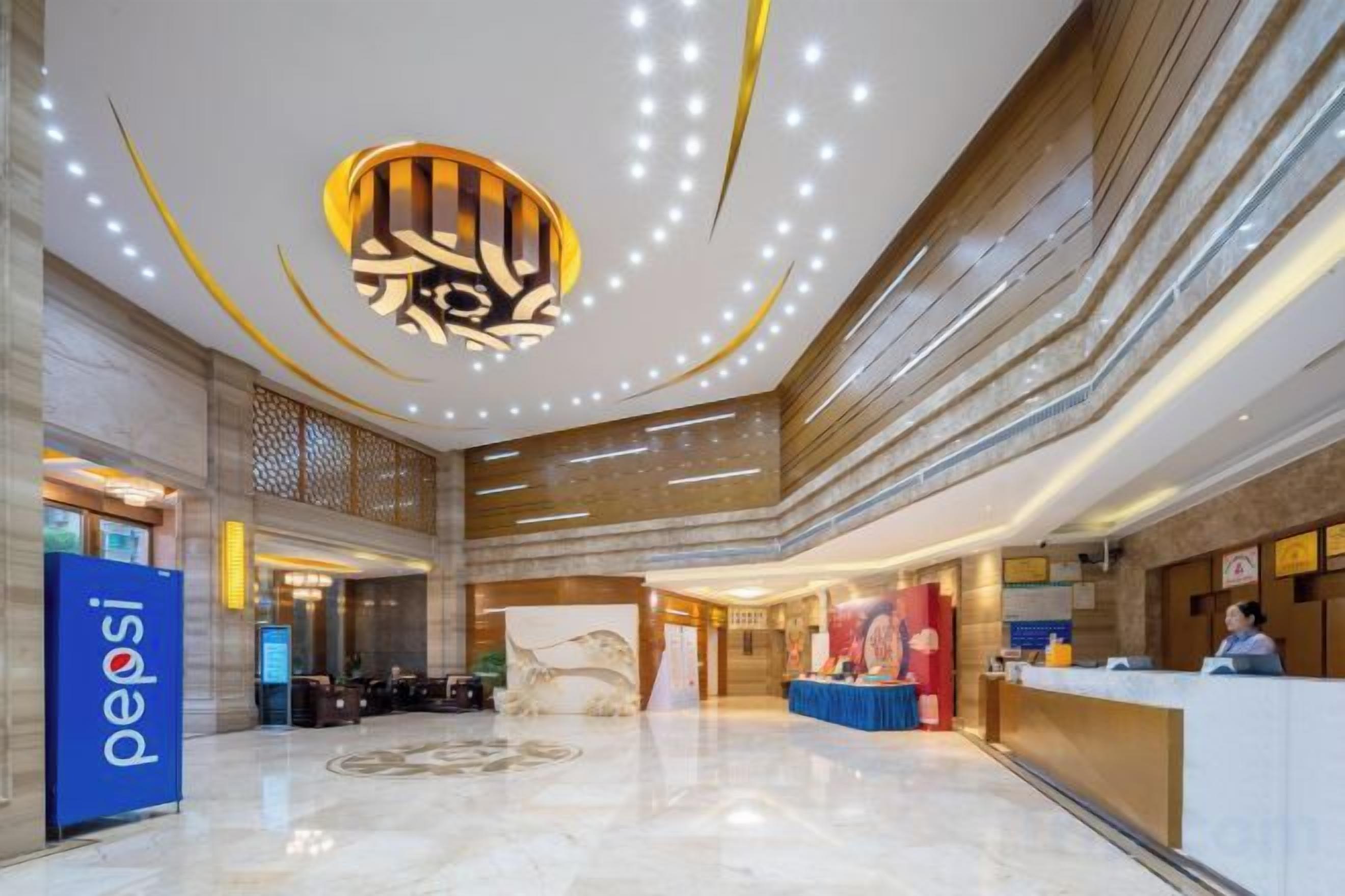 Un vestíbulo de hotel con una recepción, un techo decorativo grande y un diseño moderno.