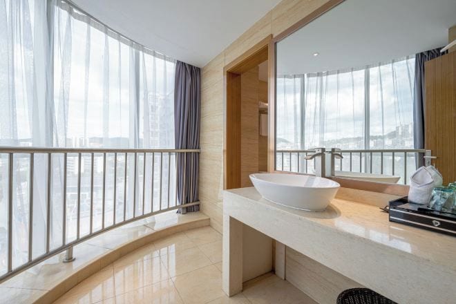 A modern bathroom with a large window, a white sink, and a mirror.
