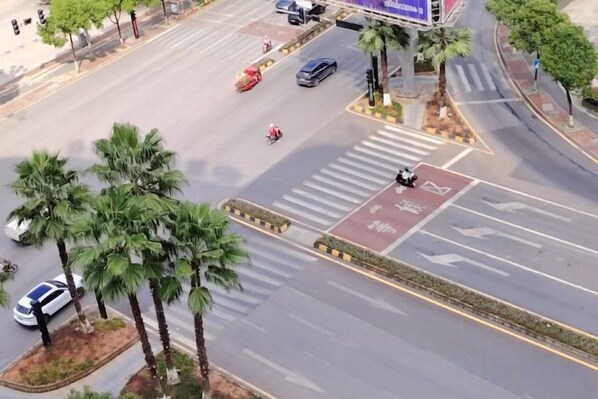 An aerial view of a street with palm trees, a pedestrian crossing, and vehicles. - Fusion International Hotel (Yizhang)