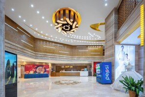 A hotel lobby with a reception desk, a large digital screen, and a decorative ceiling. - Fusion International Hotel (Yizhang)