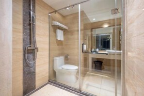 Un baño moderno con cabina de ducha de vidrio, inodoro y lavamanos con espejo.