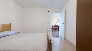 A bedroom with a bed, a wooden headboard, and a door leading to a dining area. - 2815 Villetta la Siepe - Appartamento B by Barbarhouse (Taviano)