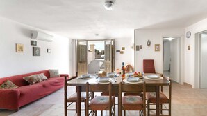 A dining area with a table set for four, a red sofa, and a staircase leading to an upper floor. - 2815 Villetta la Siepe - Appartamento B by Barbarhouse (Taviano)