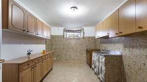 A kitchen with wooden cabinets, a tiled backsplash, a window with bars, and a sink. - 2815 Villetta la Siepe - Appartamento B by Barbarhouse (Taviano)