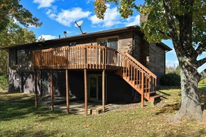 Une maison à deux étages avec une terrasse en bois et une antenne parabolique.