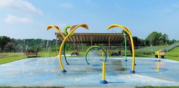 Un espace de jeux aquatiques extérieur doté de plusieurs jets d’eau et d’arcs.