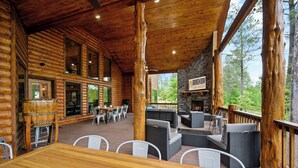 Una cabaña de madera con terraza, mobiliario exterior y una chimenea de piedra.