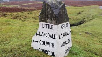 A directional signpost in a grassy field with arrows pointing to various destinations.