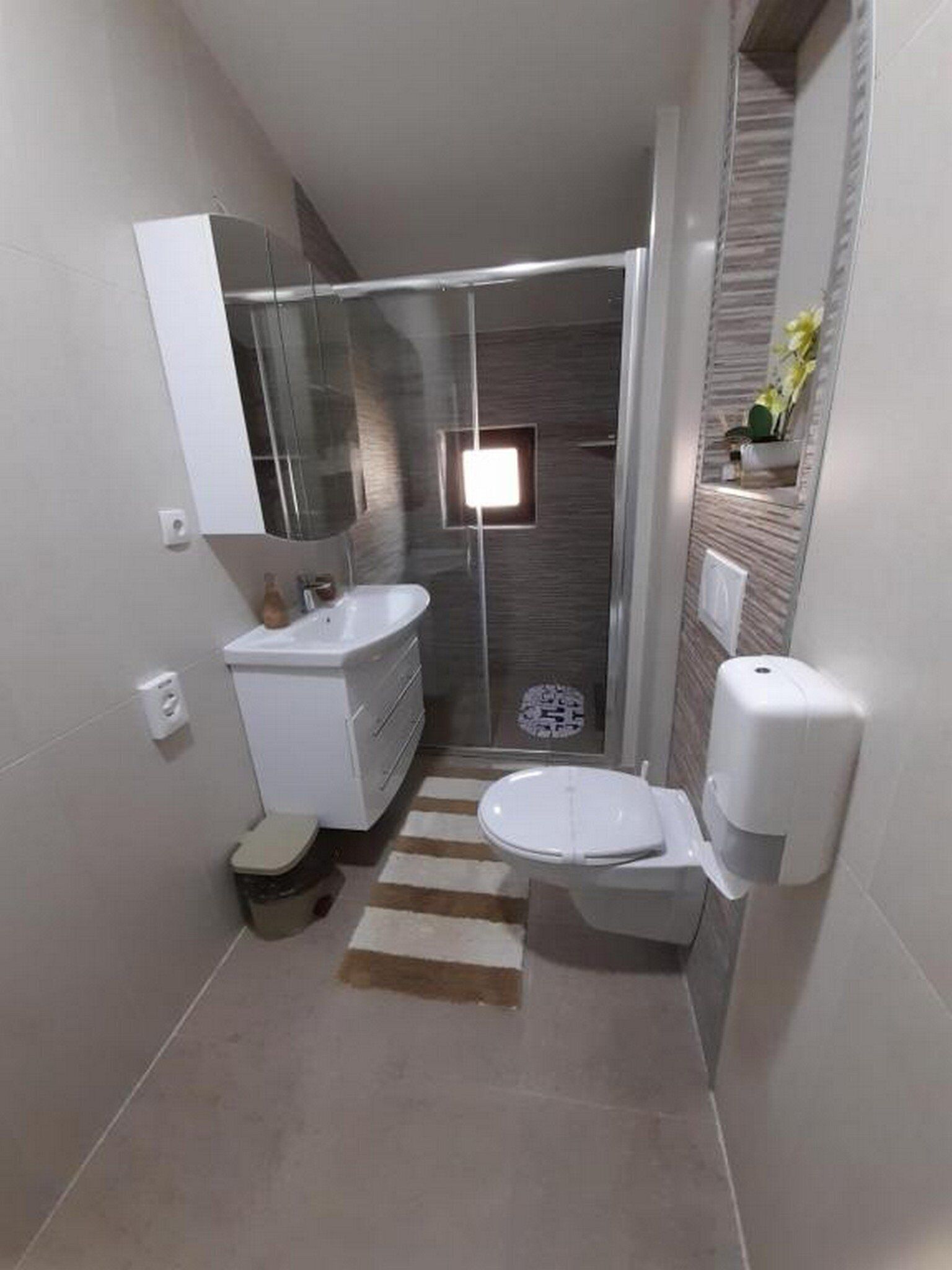 Un baño pequeño con ducha, inodoro y lavamanos.