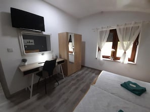 A room with a desk, chair, bed, and a TV mounted on the wall. - Apartment Dujmović 1 (Otocac)