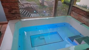 A glass-enclosed hot tub with a view of a wooden deck and outdoor area. - Apartment Dujmović 1 (Otocac)