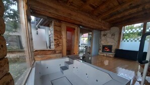 A modern log cabin with a stone fireplace, a hot tub, and a view of the outdoors. - Apartment Dujmović 1 (Otocac)
