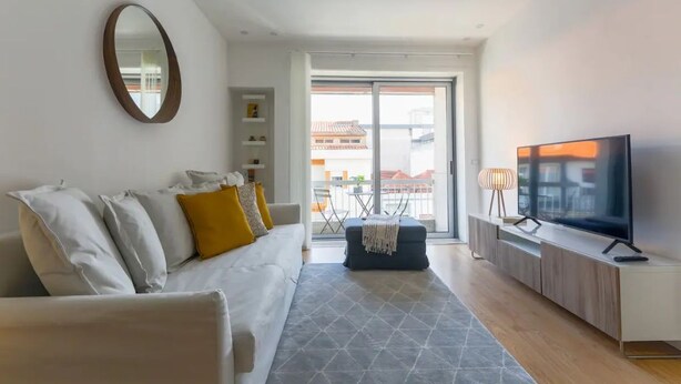 Un soggiorno moderno con un divano, una televisione e vista su un balcone.