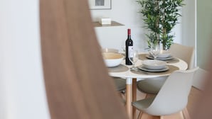 Zona pranzo con tavolo rotondo, sedie, una bottiglia di vino, un bicchiere e una pianta in vaso.